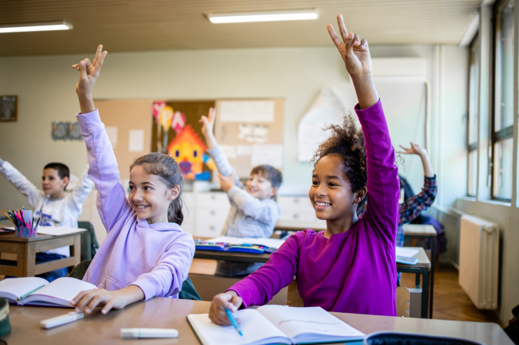 engaged classroom of middle schoolers with hands raised