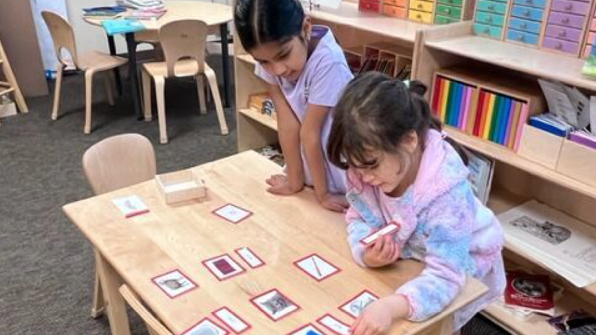 2 girls working together on a project at a classroom table|Sterling Montessori students and teacher participating in outdoor activity|Sterling Montessori logo|94 percent contactability graph|two girls working together on a lesson at a classroom table