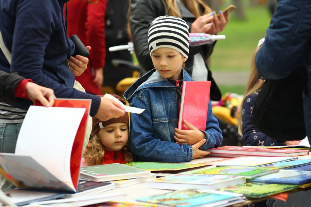 young boy and girl browsing books at book fair table