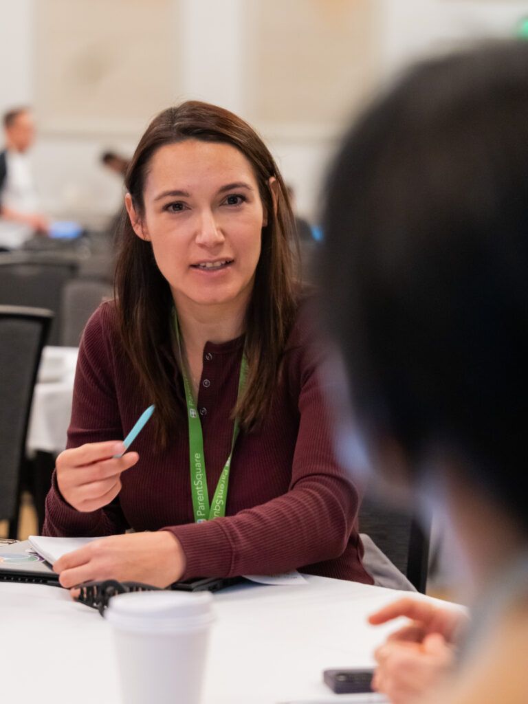 Female conference attendee engaged in conversation with colleague at table