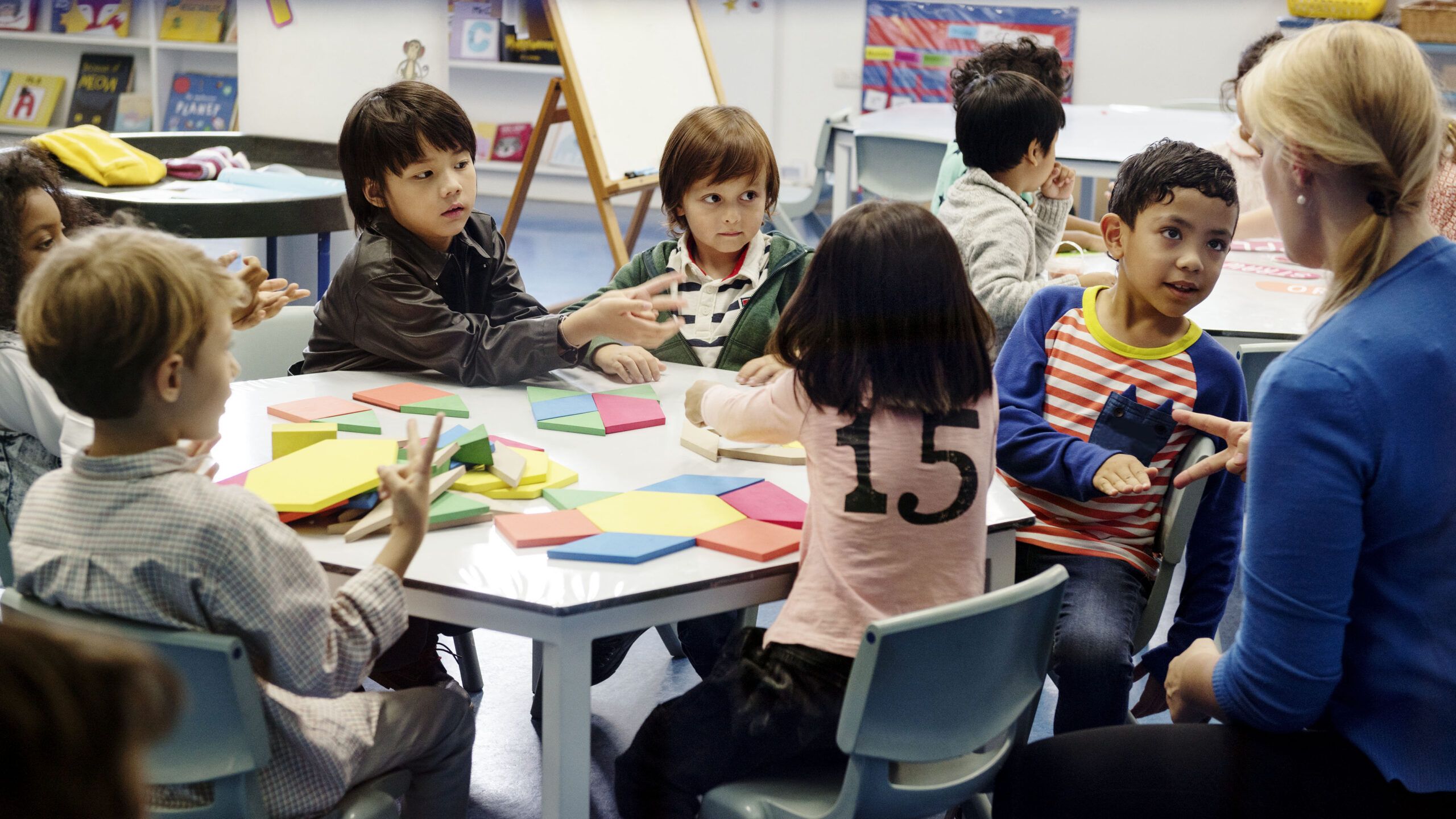 elementary school students playing with blocks around classroom table