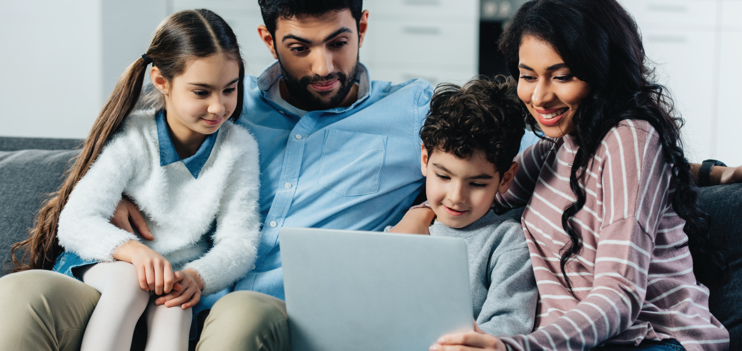 happy family gathered on couch viewing laptop